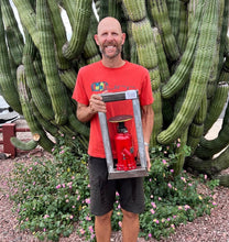 Load image into Gallery viewer, Co-Owner proudly holding early prototype of the first truly portable Hydraulic Press for Jewelery and Enamel making.